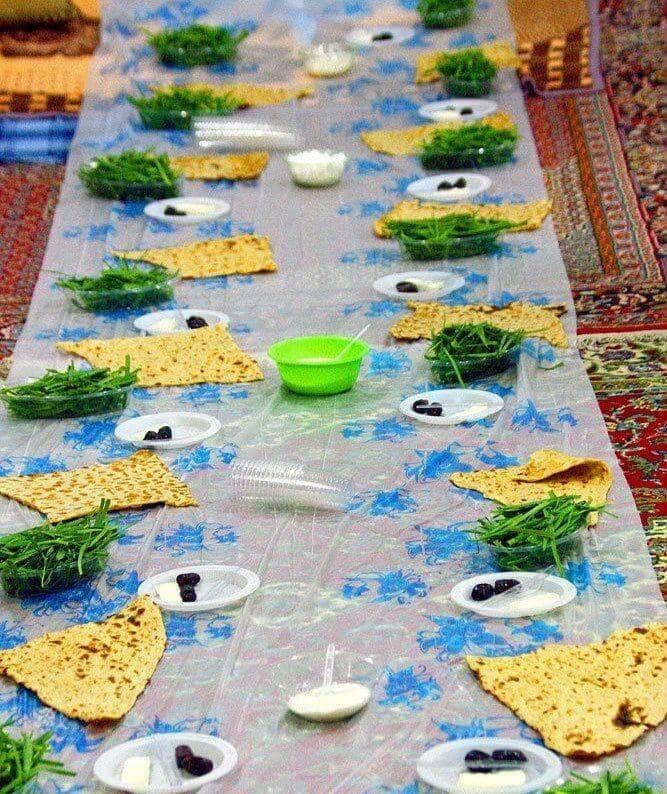 A long table setting for Iftar with flatbread, greens, and small dishes of butter and dates, prepared for fasting Muslims, enabled by crypto donations such as Litecoinin the Middle East.