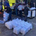 Volunteers in food distribution preparing meals for the needy during Ramadan, with crypto aided zakat support, likely using Bitcoin for donations to aid the Muslim Ummah.