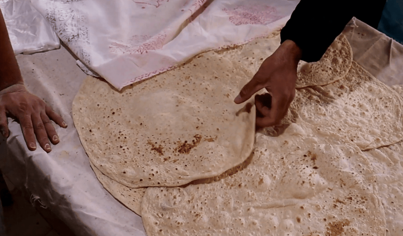 Hands processing fresh flatbread, symbolizing humanitarian aid and spiritual giving to Palestine, supported by Ethereum donations for sustenance and hope.