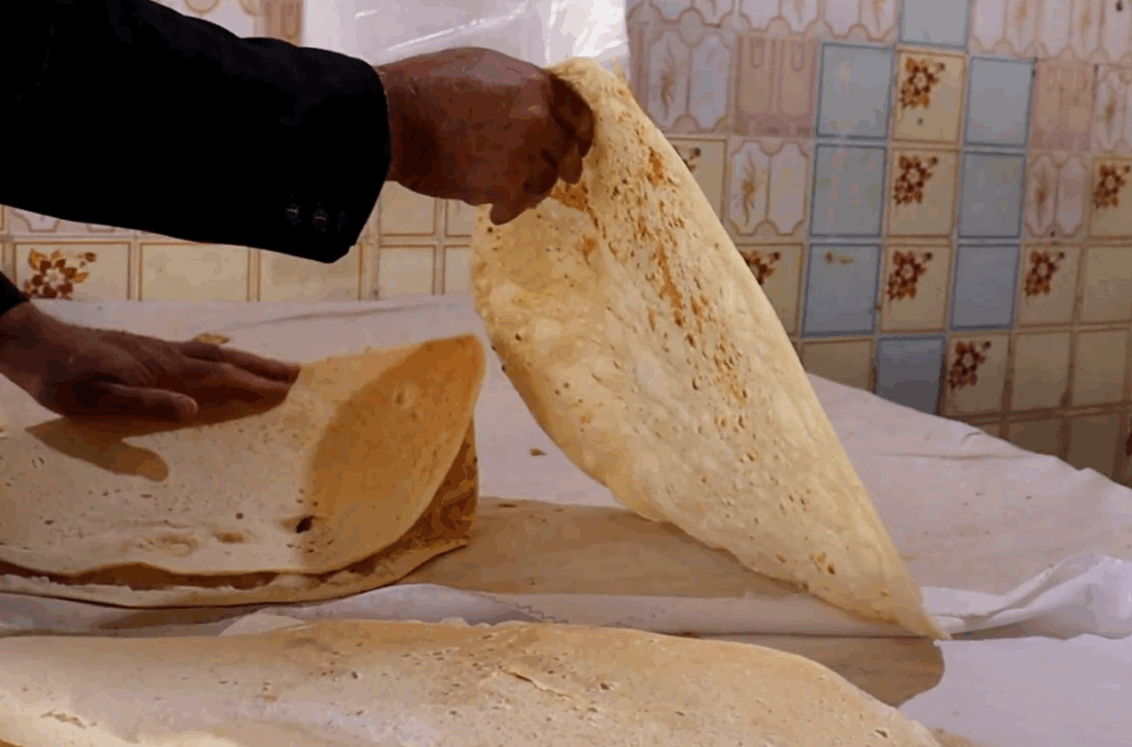 Hand holding a large flatbread, part of a humanitarian effort providing sustenance and hope to Palestinians. Crypto donations like USDT support this vital aid.