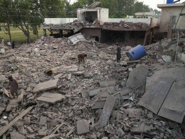 Devastated rubble of homes with people surveying the damage. Humanitarian aid for civilians in India-Pakistan conflict is urgently needed, with crypto donations like SOL making a direct impact.