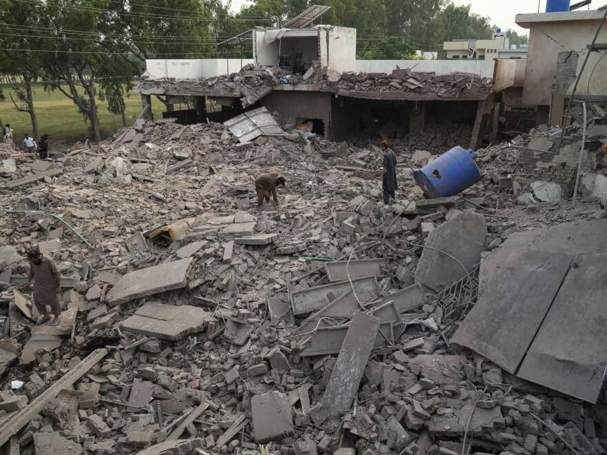 Devastated rubble of homes with people surveying the damage. Humanitarian aid for civilians in India-Pakistan conflict is urgently needed, with crypto donations like SOL making a direct impact.