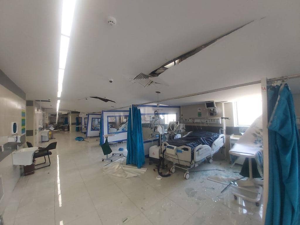 Damaged hospital ward in Tehran, Iran, showing shattered glass, debris, and a damaged ceiling, symbolizing the urgent need for aid. Donations of crypto, such as BTC, help facilitate fast relief.