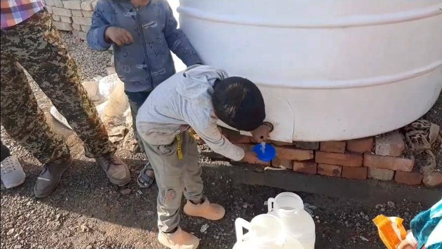 Children collecting water from a tank, symbolizing immediate relief and access to clean water through crypto donations like BTC.