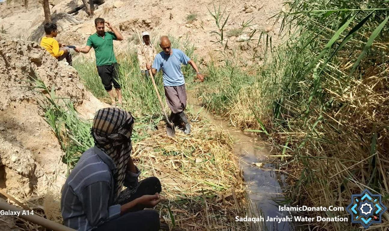 Men working to clear a water channel, contributing to Sadaqah Jariyah: Water Donation, supported by ETH.