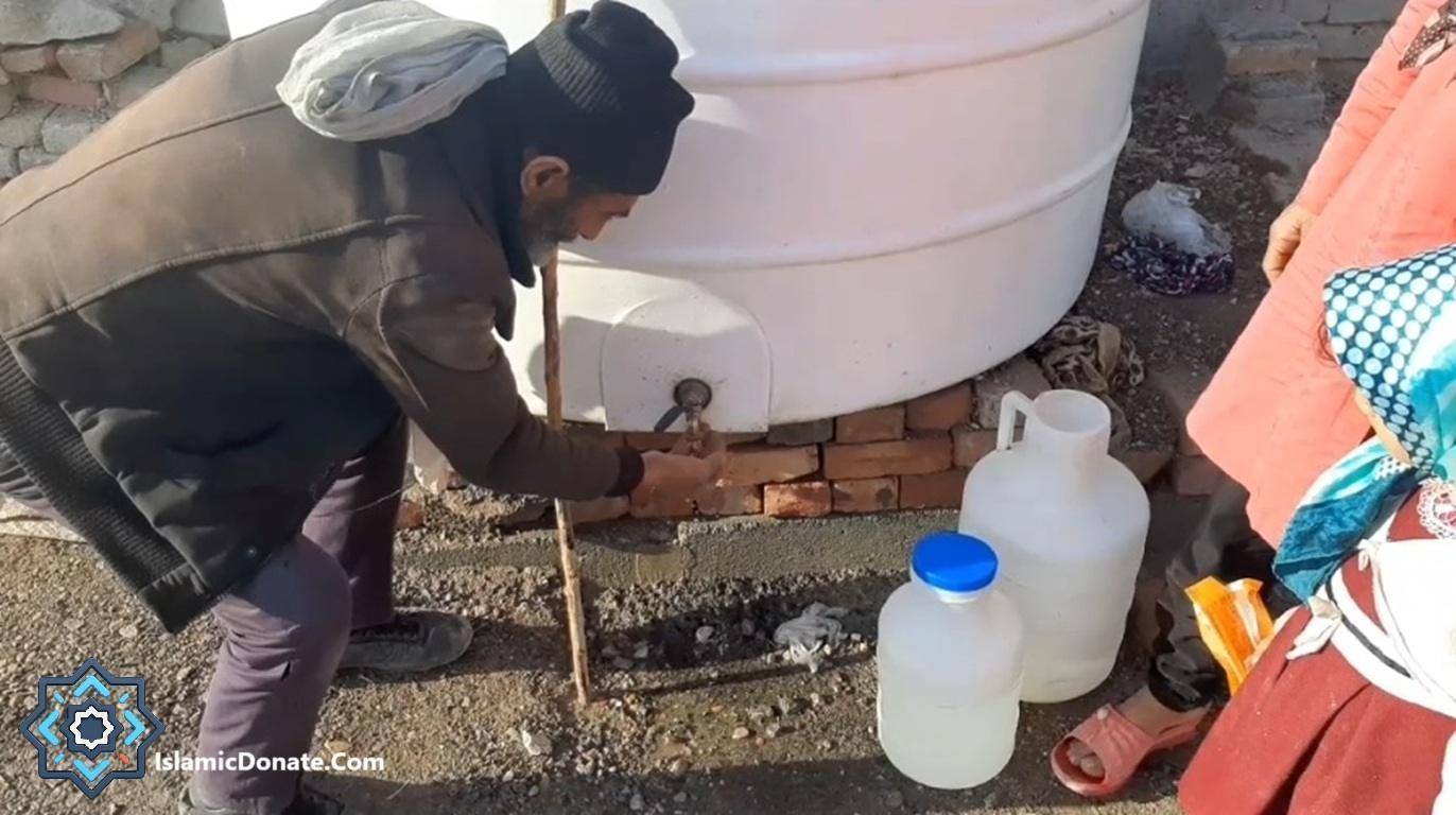 A man dispenses water from a large tank into jugs, representing direct crypto donations for clean water projects.