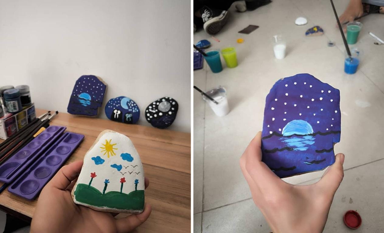 Hands holding painted rocks featuring whimsical landscapes, artistic expression and community engagement in crypto Khums donations, possibly made with WBTC.