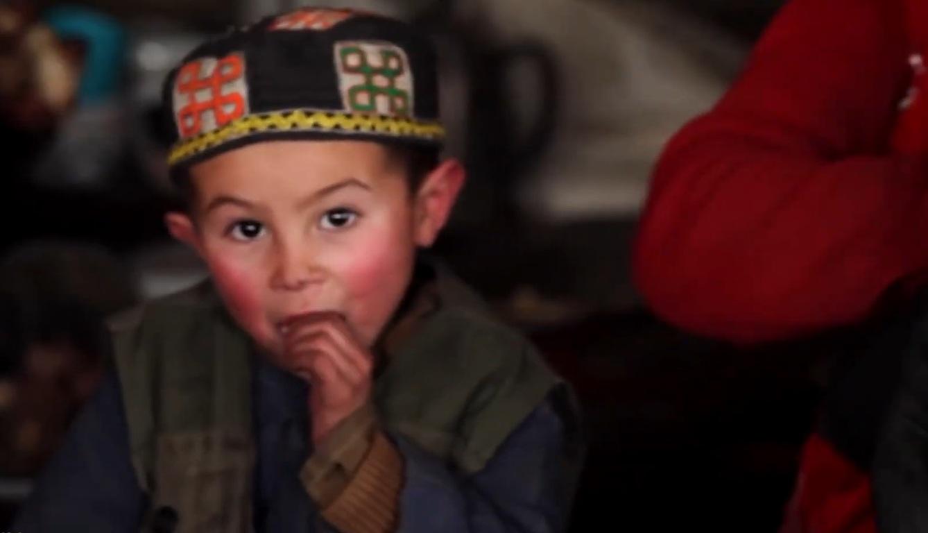 Young boy in a traditional hat eating, representing the need for Kaffarah donations to feed the poor, supported by SUI crypto.
