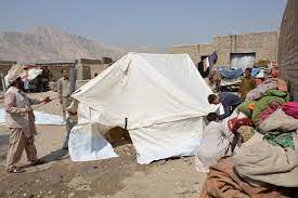 Afghan men setting up a relief tent, receiving aid for earthquake victims and displaced persons. Donate with BTC for Afghanistan's crisis.