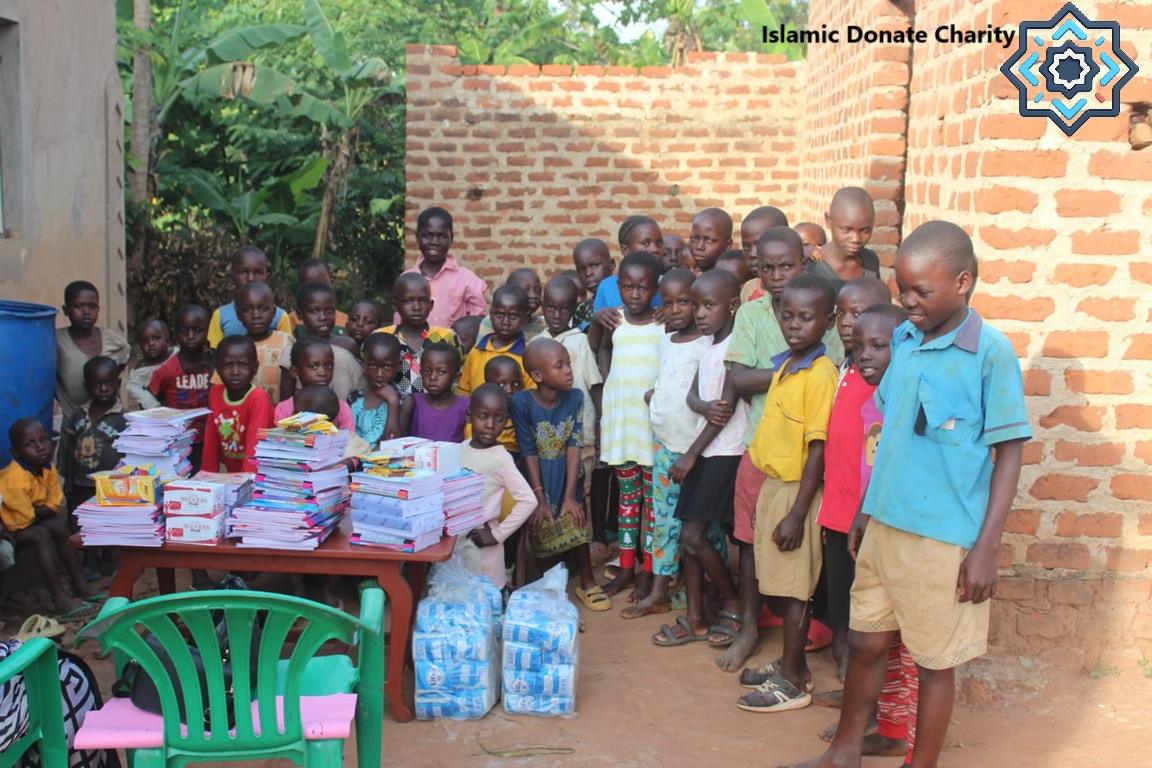 A group of children stand around a table laden with books and supplies, receiving aid. The scene implies crypto-supported kindness focused on education supplies, with SOL integrated. Keywords: Crypto Zakat, Islamic Charity, Educational Aid, Children's Support, Digital Giving.
