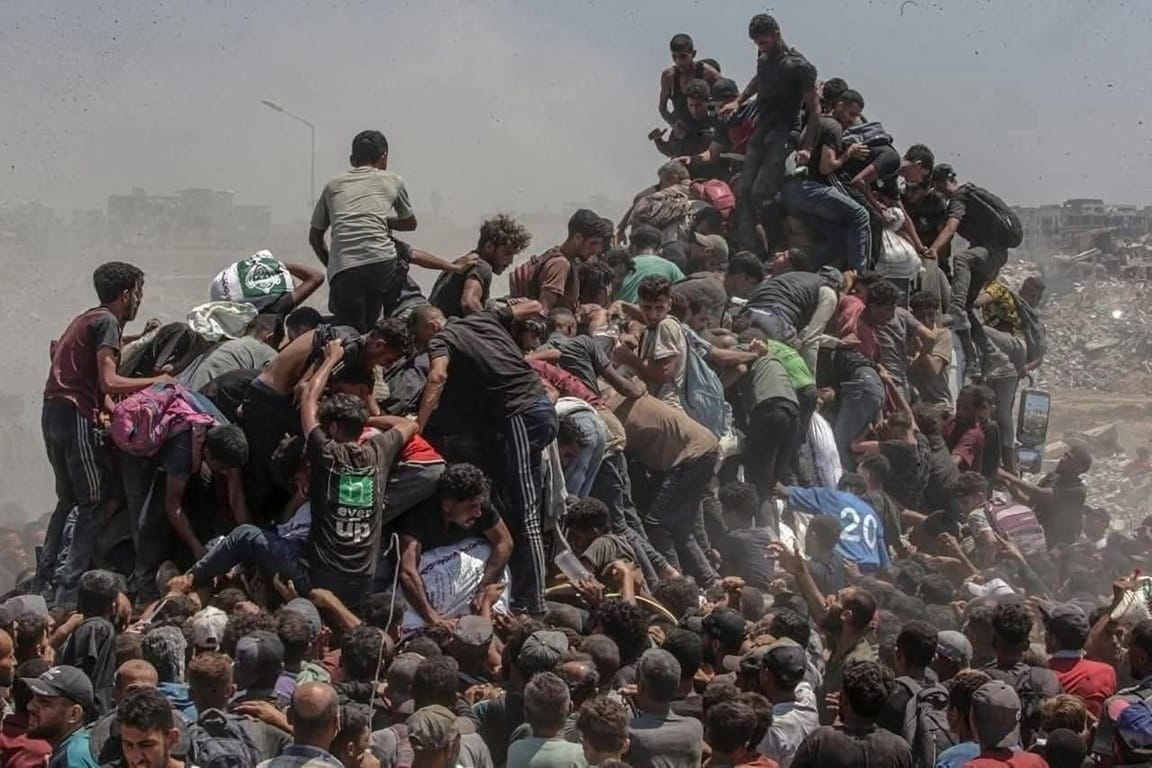 Crowd of people climbing on a pile of debris, some reaching upwards for aid in a dusty, urban environment. Daily Sadaqah with Cryptocurrency: Start A Better Day. This initiative supports feeding the needy in dire situations. Donate with USDC.