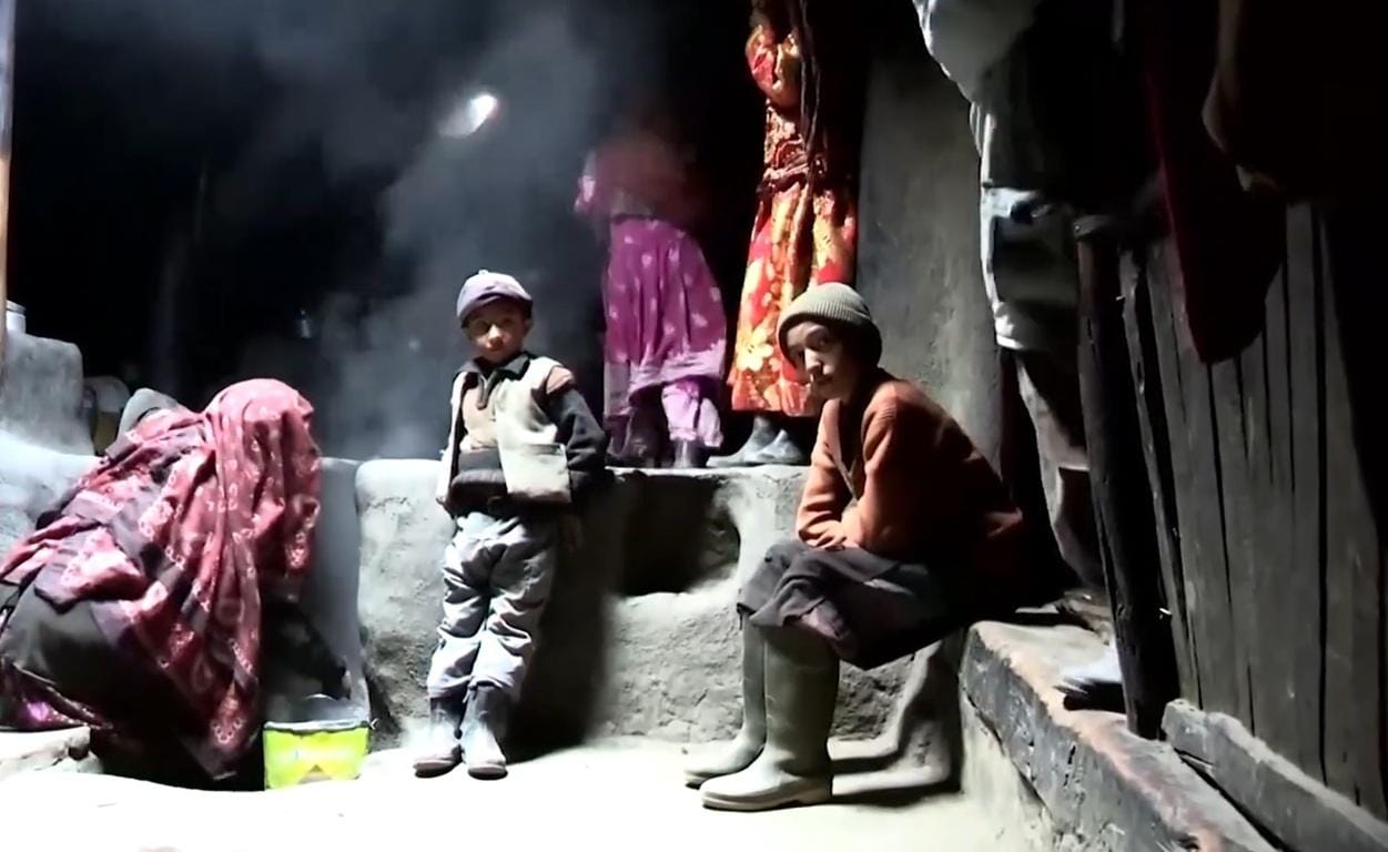 Children and adults in a dimly lit, rustic setting, with steam or smoke visible. This scene depicts recipients of Qurbani donations, benefiting from crypto giving facilitated by Islamic charitable organizations, reaching families in need with aid, food, and mercy.
