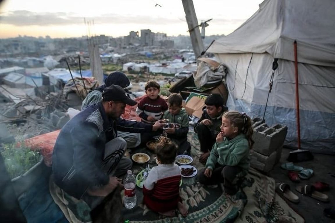 Donate USDT to help Rafah families in Gaza displaced to tents. A father feeds children near emergency relief shelters.