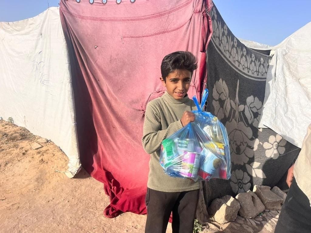 Help Rafah boy holding food aid bag for immediate relief with USDT crypto donation. Emergency food for Gaza children.