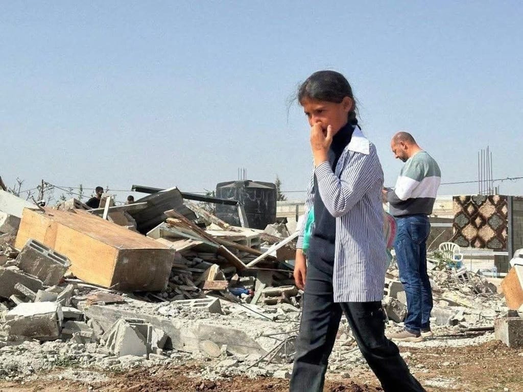 Help Rafah girl walking past rubble of destroyed home with TRX for urgent crypto relief and food aid for Palestine families.