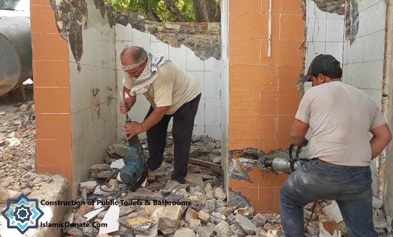 Construction workers demolishing a damaged structure to build new public toilets and bathrooms, with a focus on improving sanitation for displaced families. Donate with RLUSD.