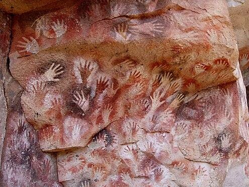 Cave dweller's handprints symbolizing immortality and leaving a legacy, aided by crypto donation processing on Solana.