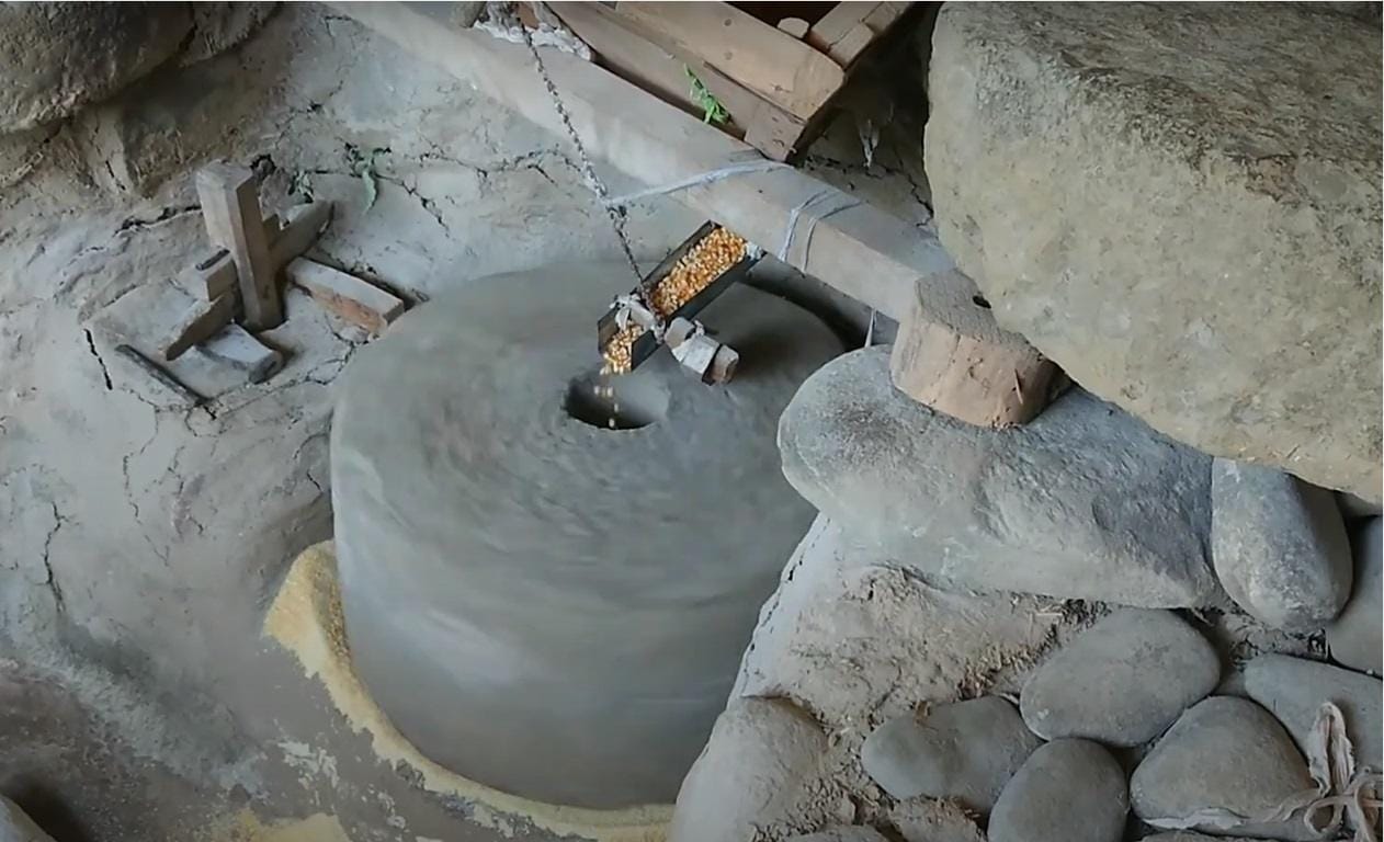 Traditional stone mill processing 900 kilos of corn, supporting local farmers and providing meals for the needy, with crypto donations enabling this charitable impact via ETH.