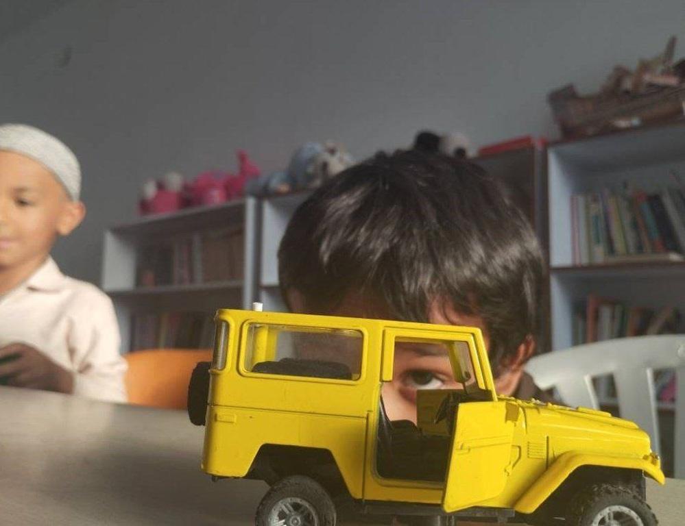 Children playing with a yellow toy car, anonymous crypto donations for a better future, potentially via Bitcoin.