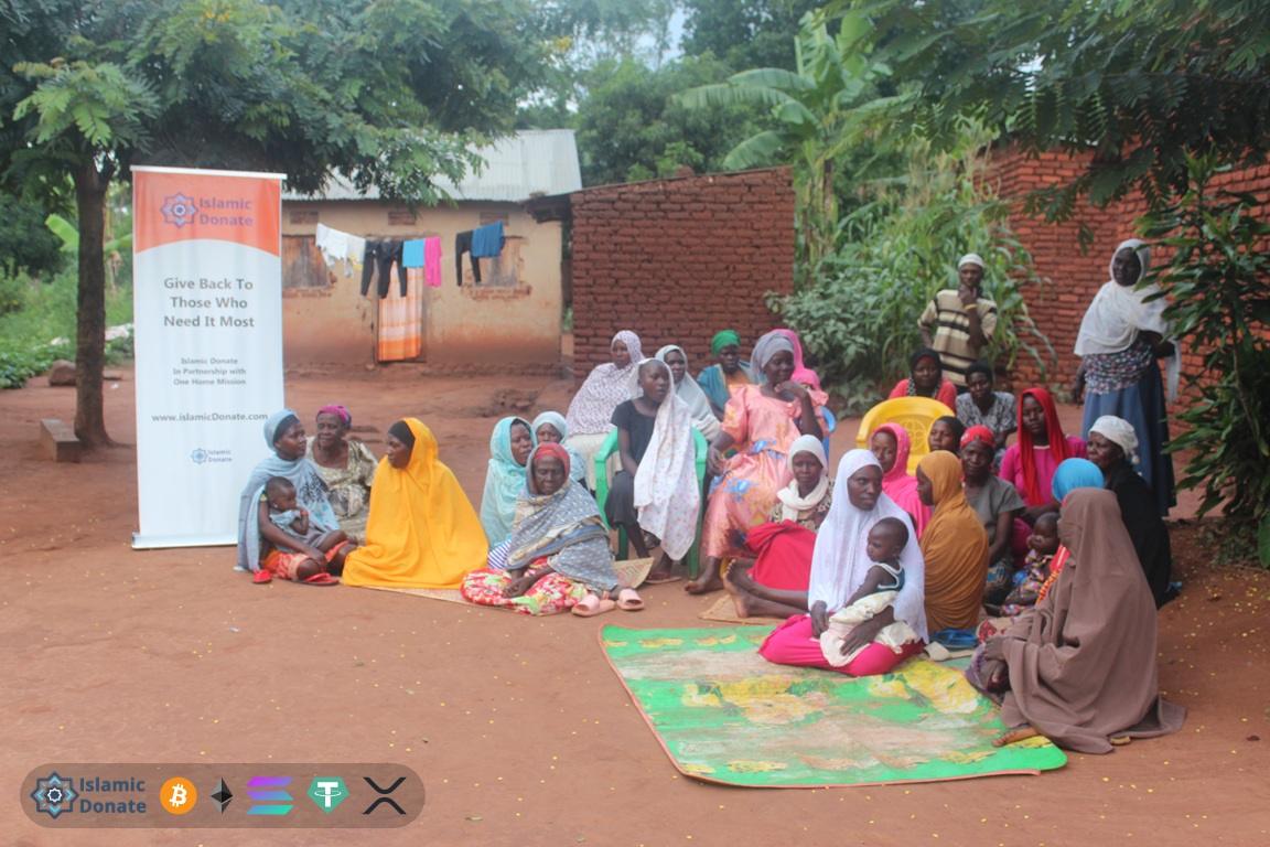 Zakat online with USDT funds women and children sitting by a banner providing aid to the needy and poor in rural settings.