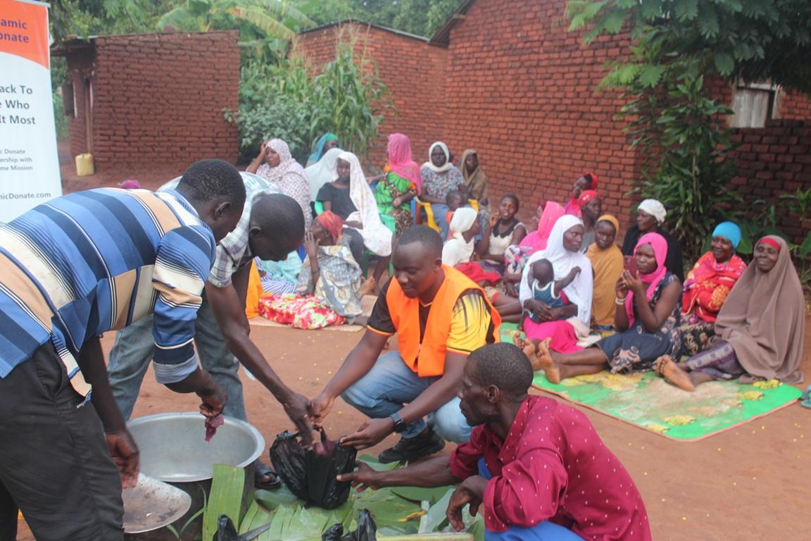 Men preparing meat for distribution to a seated group of women and children, representing community-based Islamic charity and Qurbani donations facilitated by cryptocurrency like Litecoin.