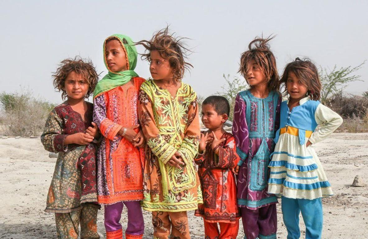 Group of children in colorful traditional clothing standing outdoors, showing vulnerable Muslim children receiving aid through crypto donations like TRX.