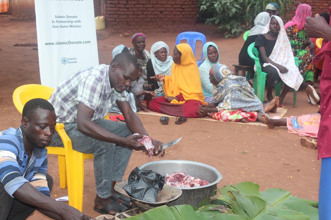 Man cuts meat for qurbani donation. Local community members gather to receive aid, with crypto donations facilitated via Dogecoin.
