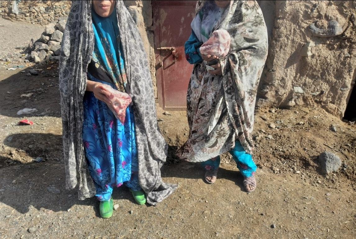 Two women in traditional clothing holding packages of meat, symbolizing zakat and aid distributed to the needy, crypto donations like BTC.