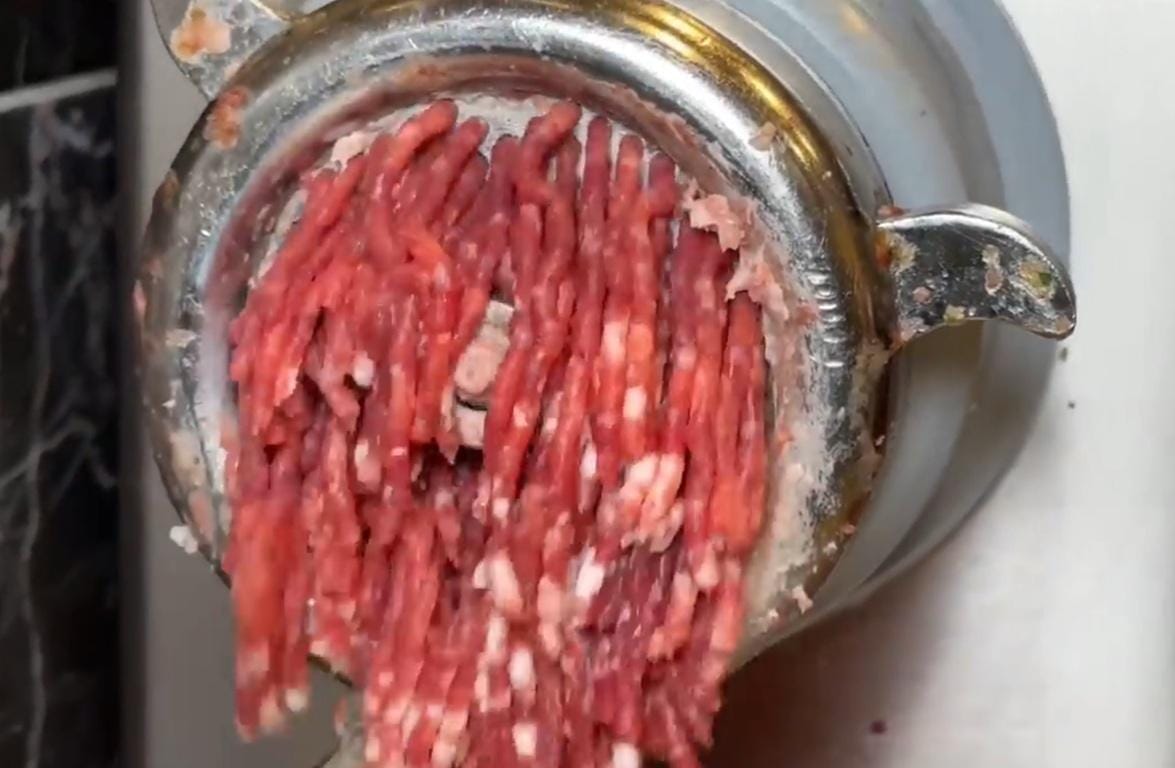 Mincemeat is processed through a meat grinder, symbolizing the distribution of Qurbani meat donations made via cryptocurrency and accepted in USDT.
