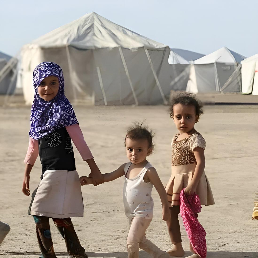 Three young children walking in front of refugee tents in Yemen, symbolizing hope and resilience. Your crypto donation, potentially via BTC, provides essential aid like food, water, and shelter.