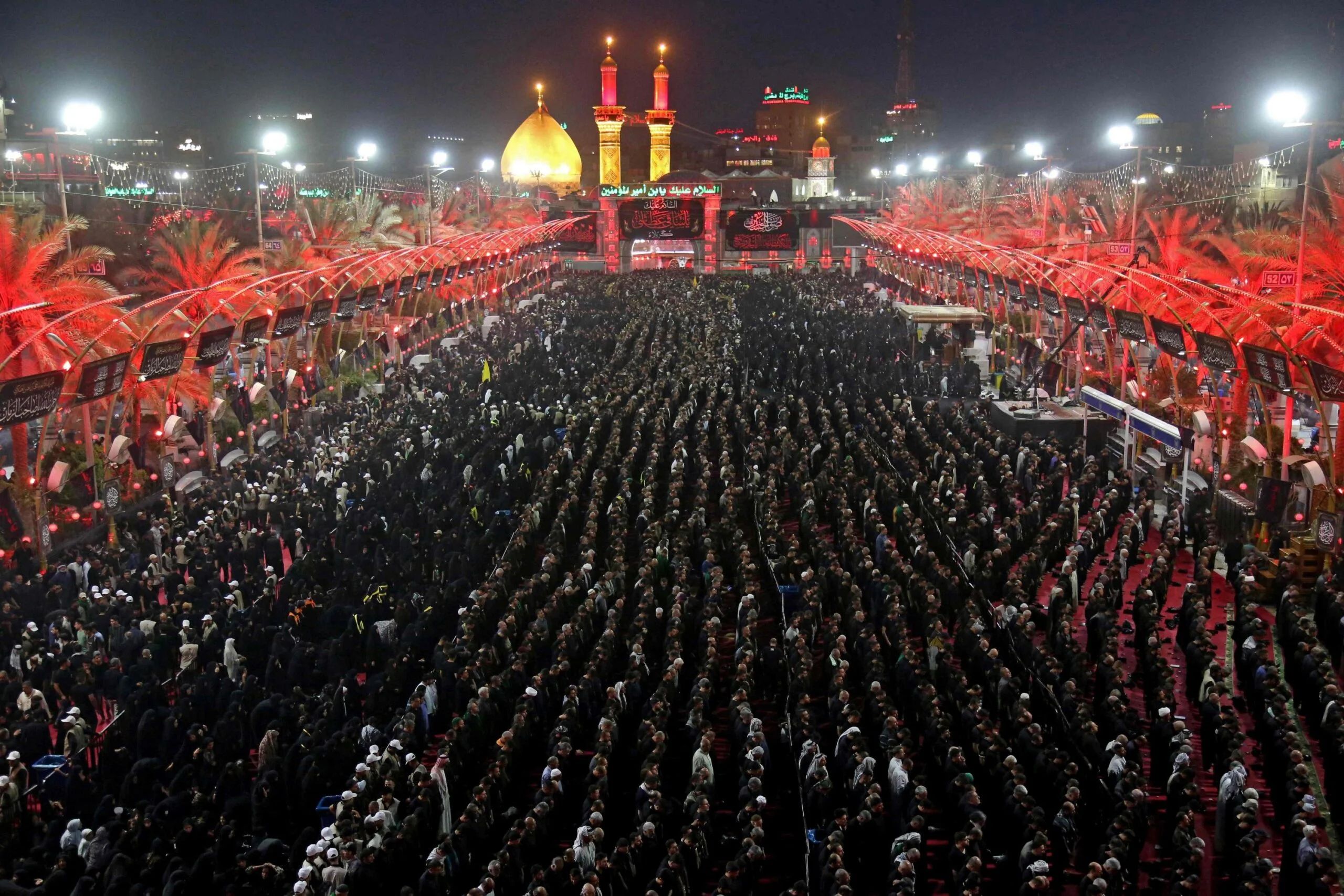 A massive gathering of people in prayer during a religious event, with illuminated minarets and a golden dome in the background. Crypto donations are accepted, supporting the cause via USDT. The event honors Imam Hussein.