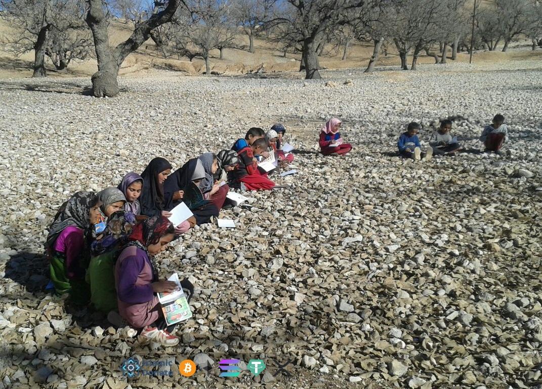 Children in rocky fields and read books funded by USDT donations for education.