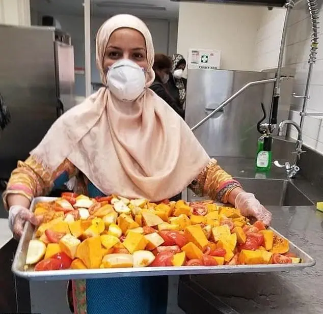 A masked woman in a hijab holds a tray of chopped vegetables, implying food aid supported by USDT donations for hot meals.