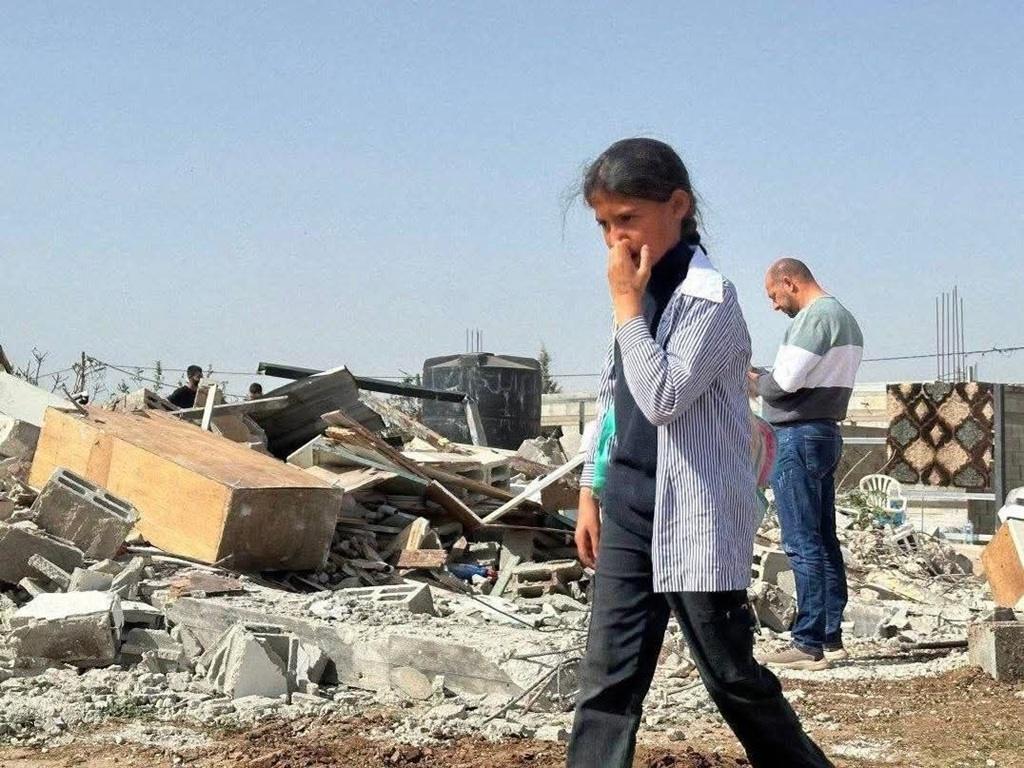 Help Rafah girl walking past rubble of destroyed home with TRX for urgent crypto relief and food aid for Palestine families.