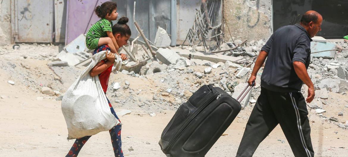 Displaced Gazans carry belongings through rubble, with crypto donations via USDT providing essential aid to those in need for water, food, and shelter.