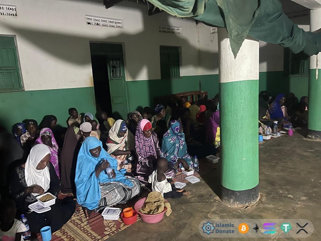 Ramadan fasting community support in indoor gathering. Iftar relief for needy families sharing meals donated via Tether.