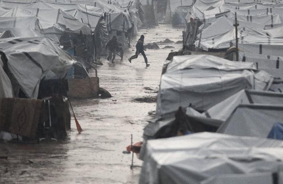 Winter relief camp for displaced families in rainy conditions. Aid provides warm clothing, shelter, and heating. Donate crypto like BTC to help vulnerable communities.