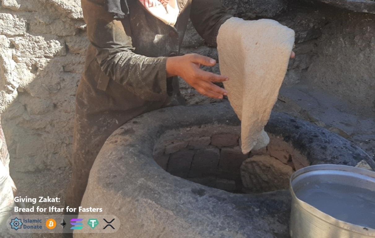 Woman bakes dough in a stone oven for needy fasting families. Give Zakat in Ramadan bread for Iftar funded by XRP.