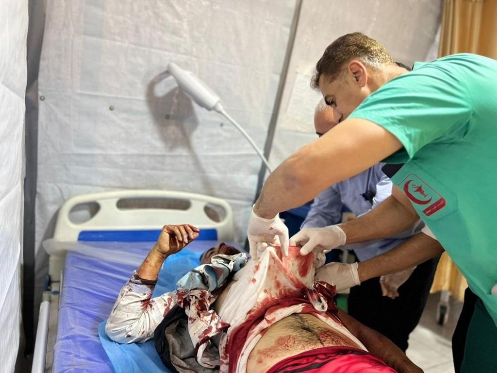 Doctors provide emergency medical aid to an injured Palestinian patient using ARB crypto support for essential supplies.