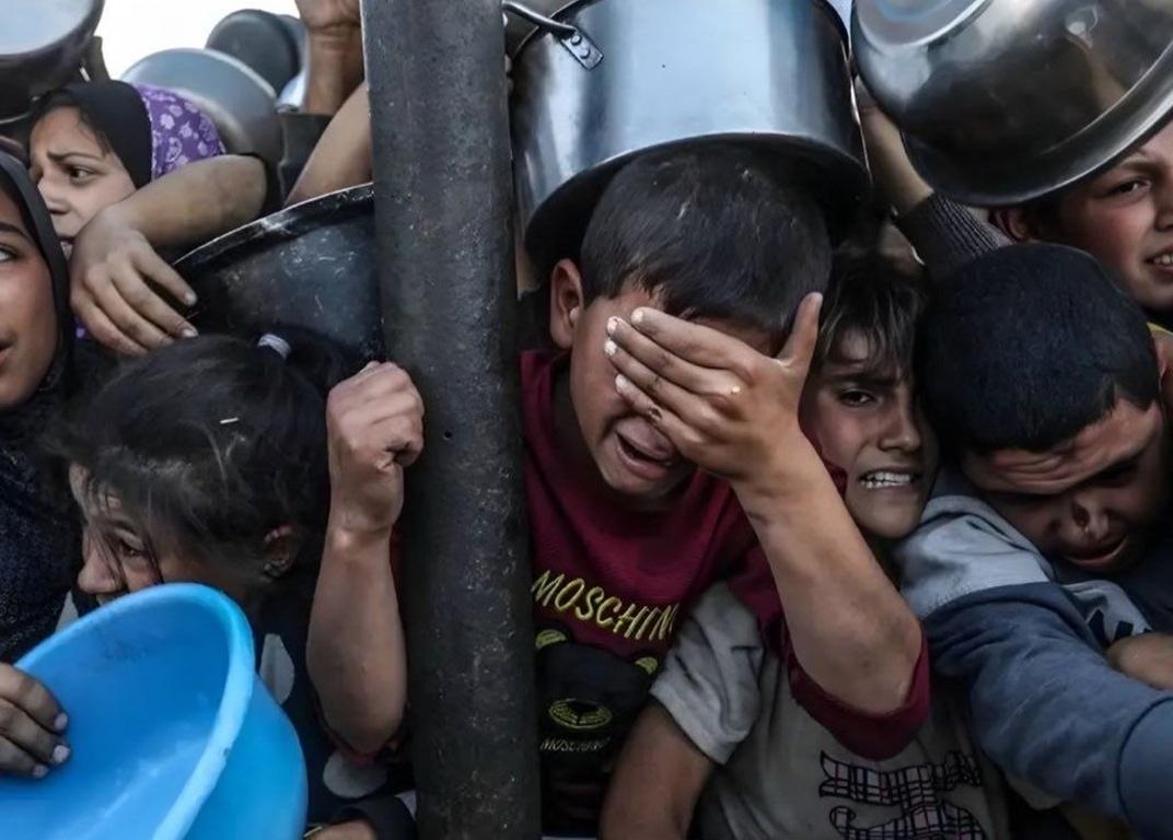 Crying children waiting in line hold empty pots for food aid in Palestine supported by Litecoin Zakat donations