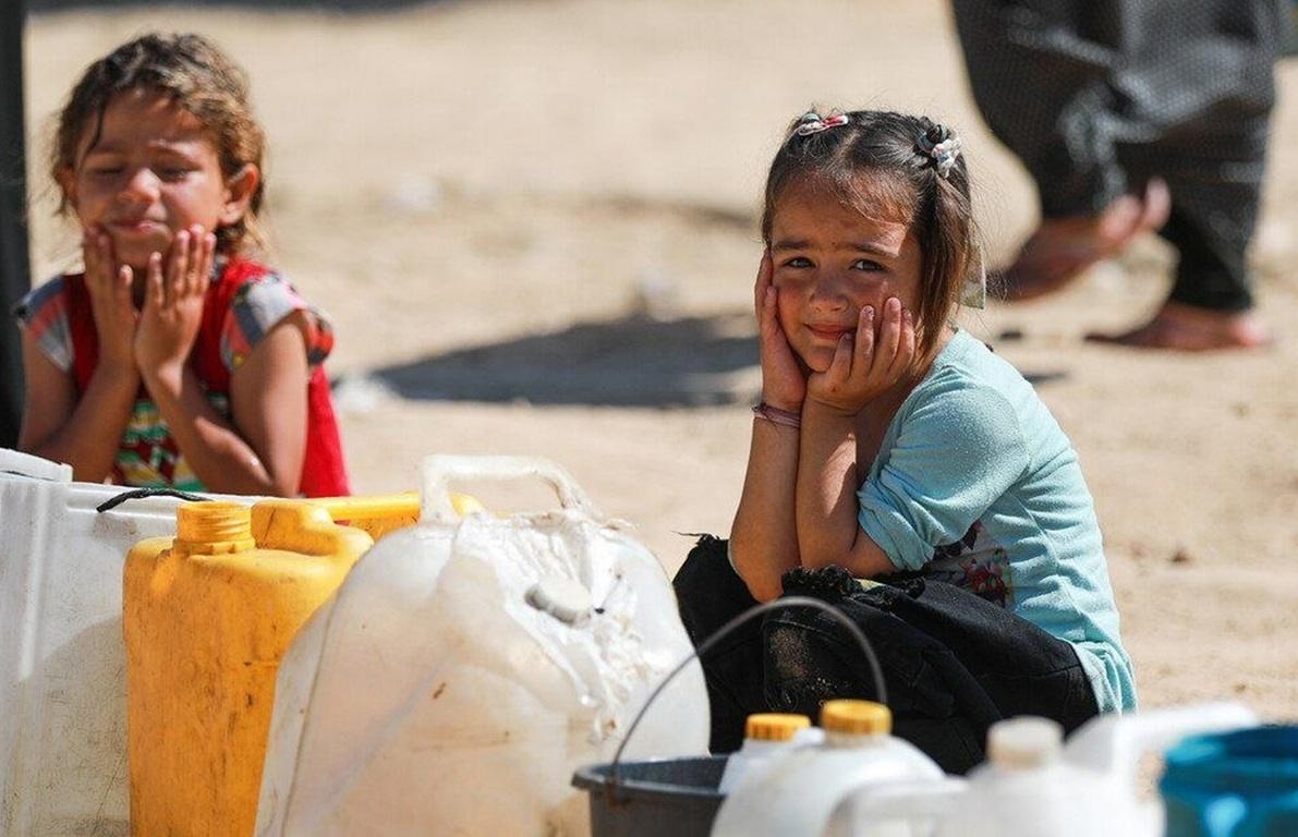 Palestinian children wait for clean water with supply jugs where donors provide support via USDT for humanitarian aid.