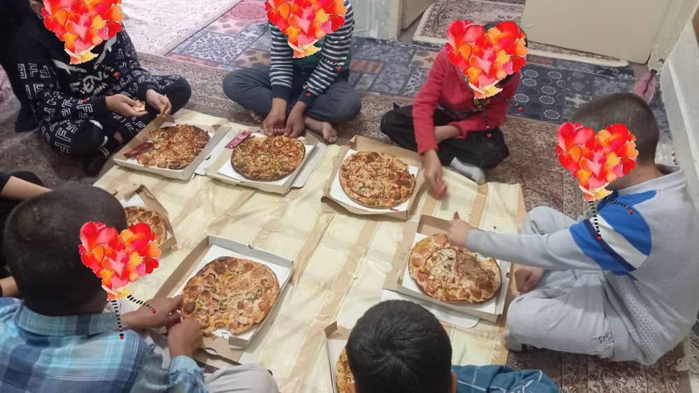 Children sitting on the floor surrounded by pizzas, many enjoying their first taste. Bitcoin Pizza Day charity initiative.