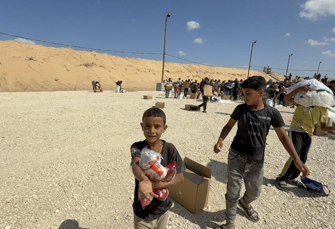 A boy holds food relief packages at a secure delivery site. Silent giving saves children through Ethereum crypto donations.