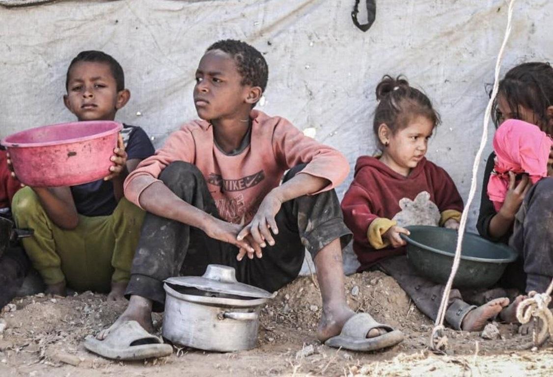 Refugee children with empty bowls. Support humanitarian aid using USDC for secure impact.