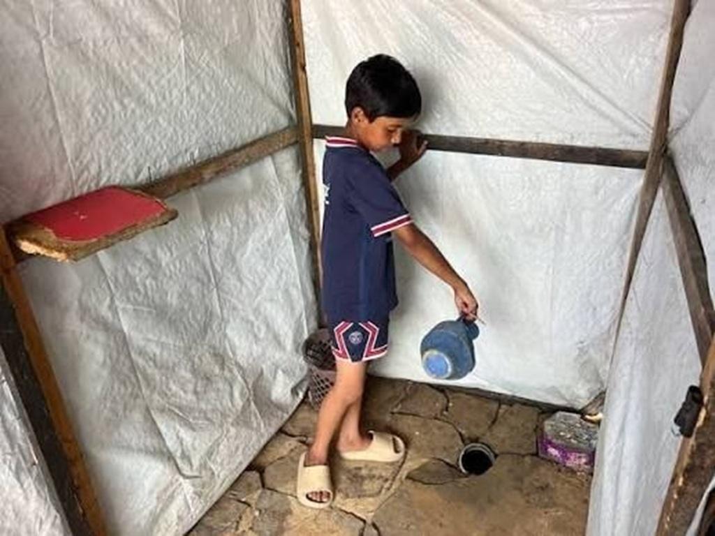 Gazan child in a makeshift field bath prevents disease hazards. Help Gazans survive summer heat in displacement camps via Bitcoin.