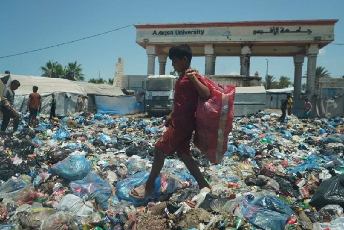 Child scavenging garbage at Al-Aqsa University in Gaza refugee camps needs relief. Support with USDC for sanitation.