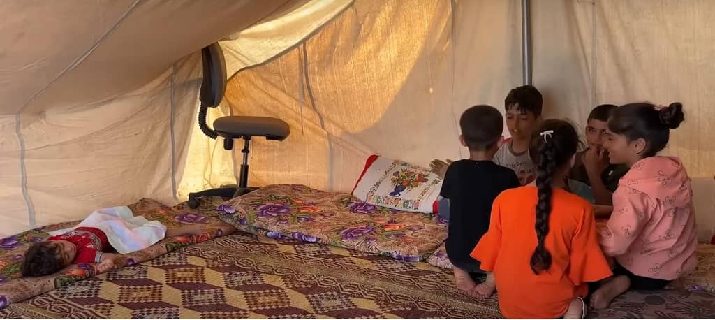 Children gather in a tent in Palestine for education. Support vital aid delivery with crypto donations, such as BTC, to help overcome obstacles.