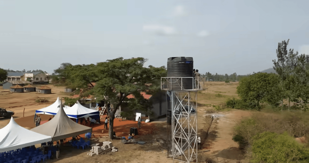 Community water well tower with people working, clean water access and Sadaqah Jariyah, enabled by crypto donations like USDT.