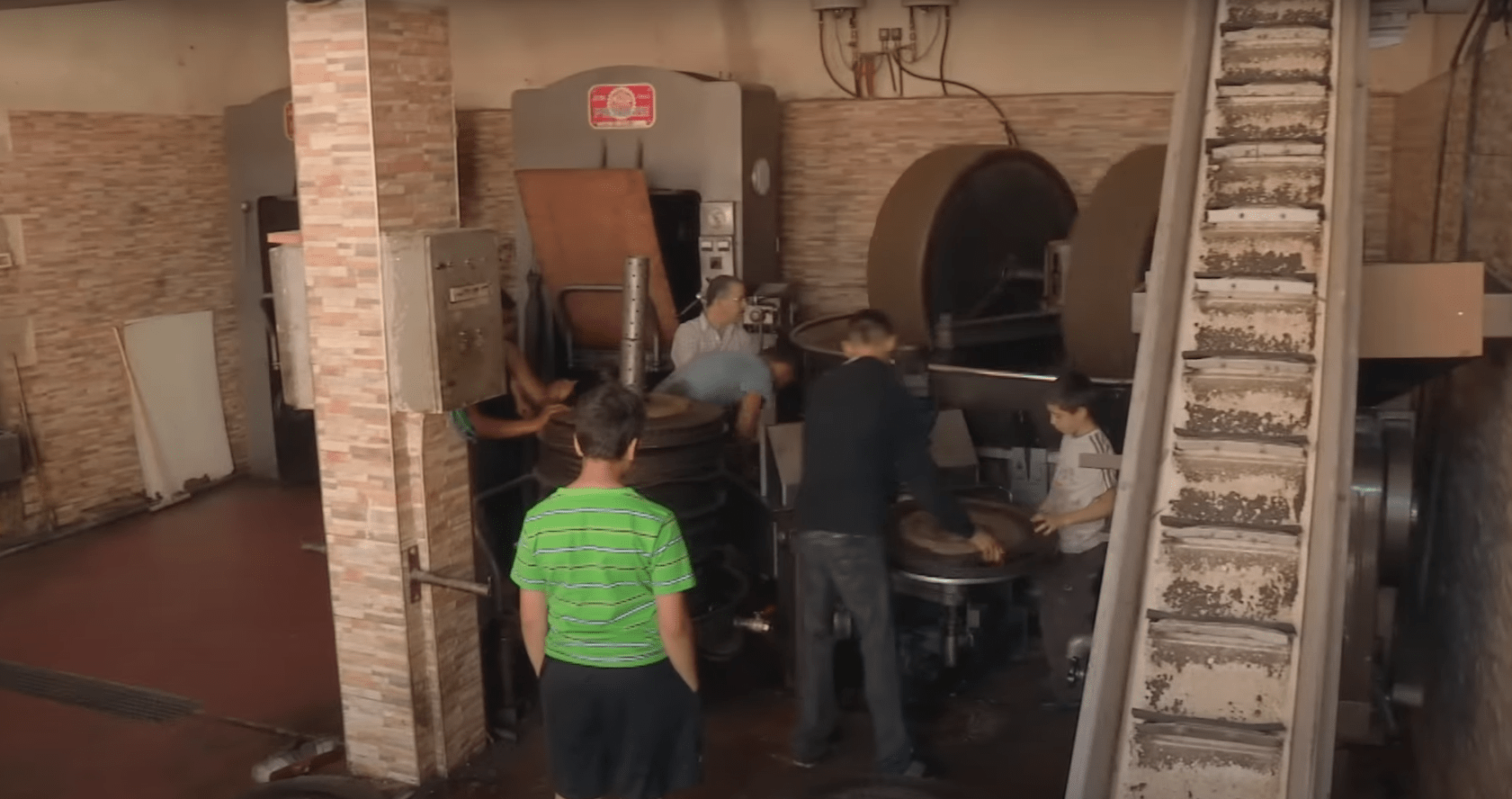 Syrian workers operating machinery in a restored olive oil workshop, receiving crypto donations for sustainable livelihoods via Ethereum.