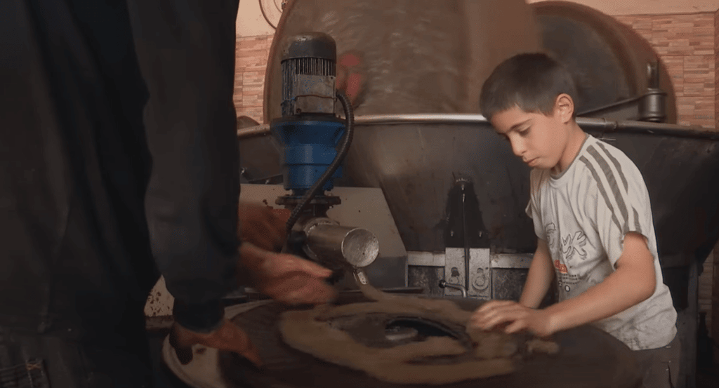 Syrian boy works in a restored olive oil workshop, a Sadaqah Jariyah project, supported by crypto donations via USDT.
